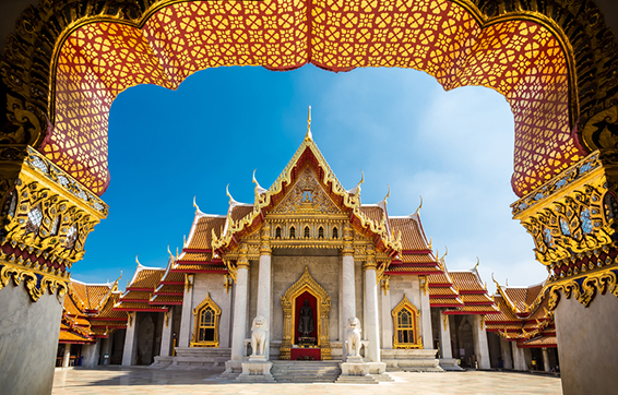 Marble Temple near Oaks hotels Bangkok with golden archways and lion statues outside in sunshine with blue sky in background